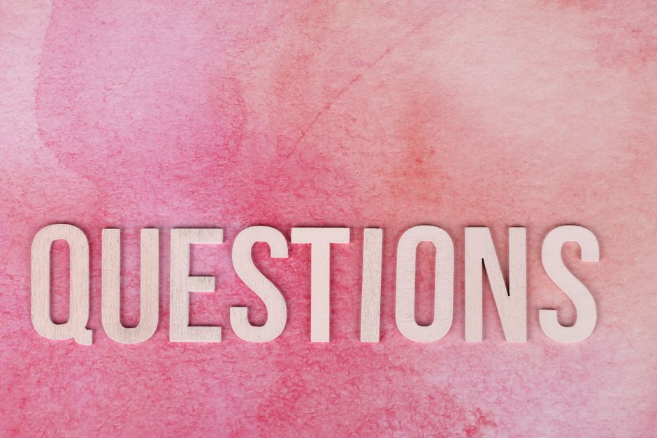 Wooden 'QUESTIONS' text on pink watercolor background, perfect for design and art concepts.